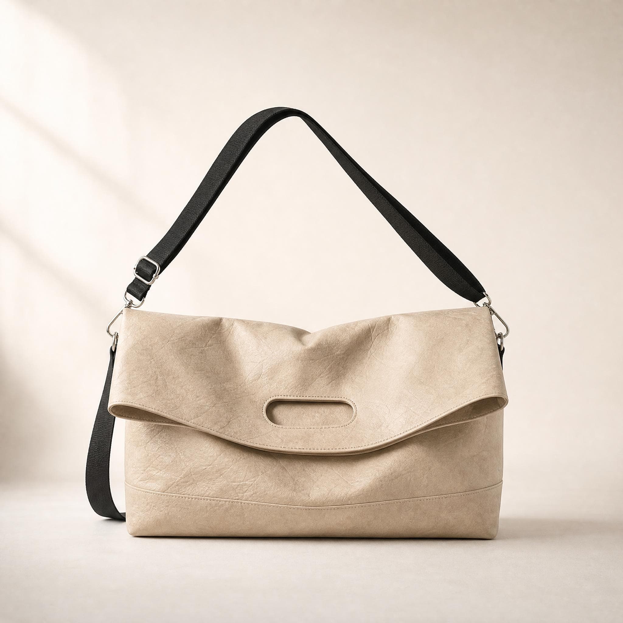 Beige crinkled fold-over messenger bag, front view on a beige background