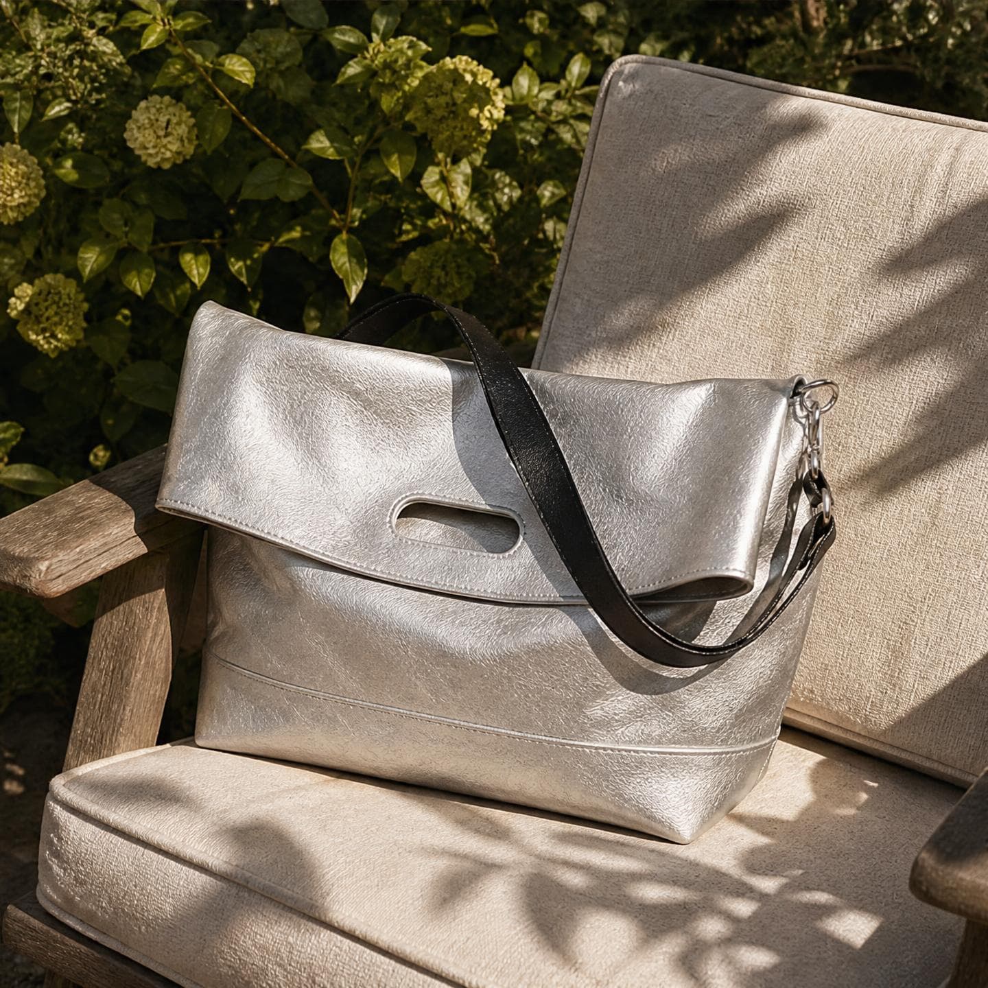 The silver bag styled on a sunlit garden chair surrounded by greenery