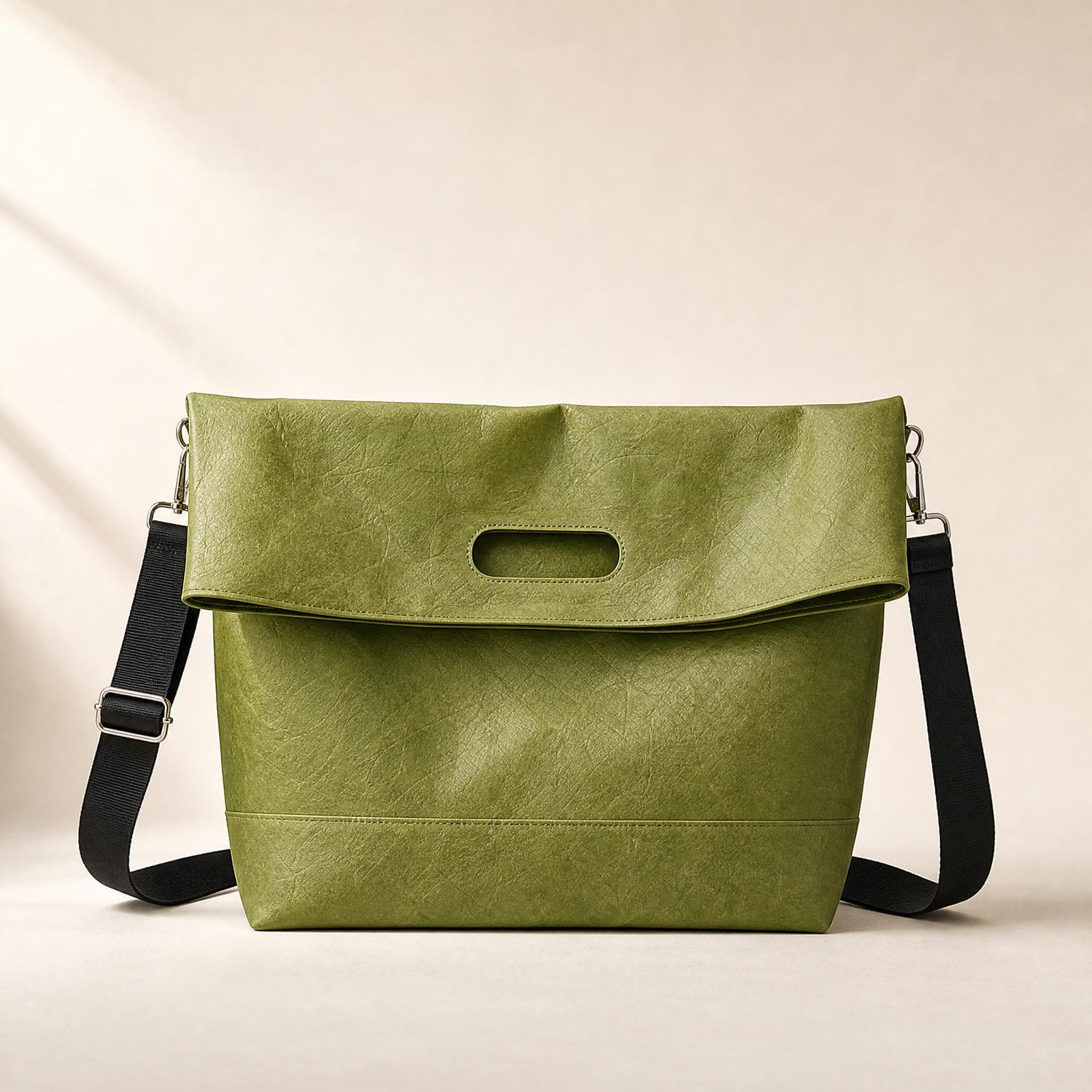Green crinkled fold-over messenger bag, front view on a beige background