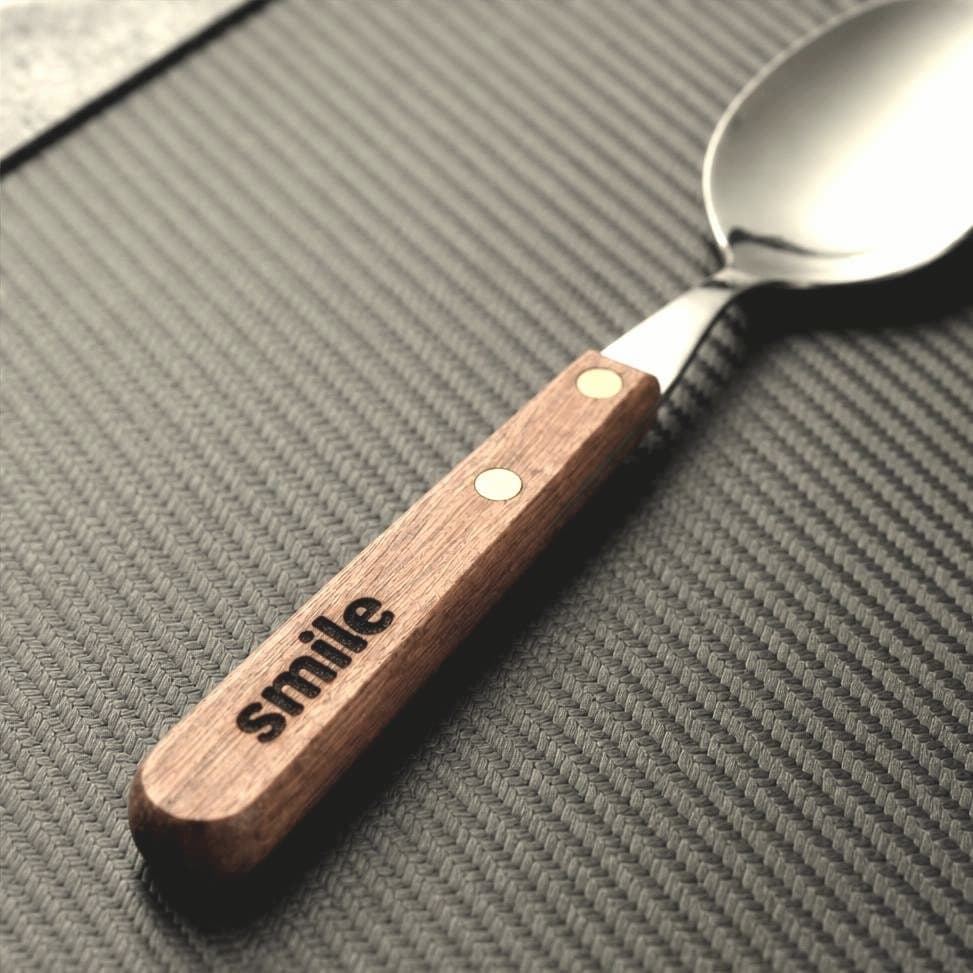 Finished wooden-handle spoon with the word smile laser-engraved on the handle