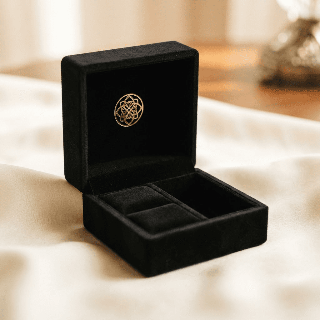 Premium black velvet jewelry box with a gold foil logo on a cream silk surface