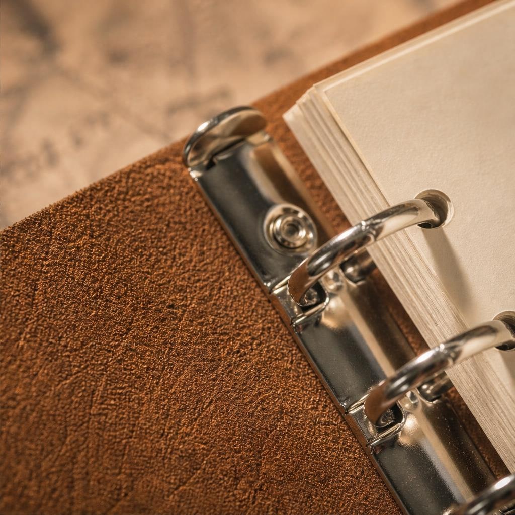 Close-up of silver 6-ring binder mechanism and cream paper inside the leather cover