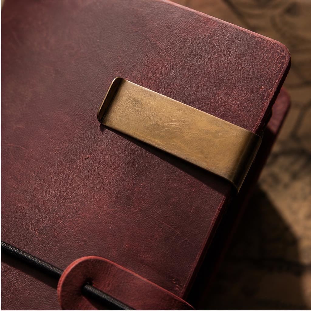 Close-up of red-brown chestnut leather with a brass clip and elastic closure